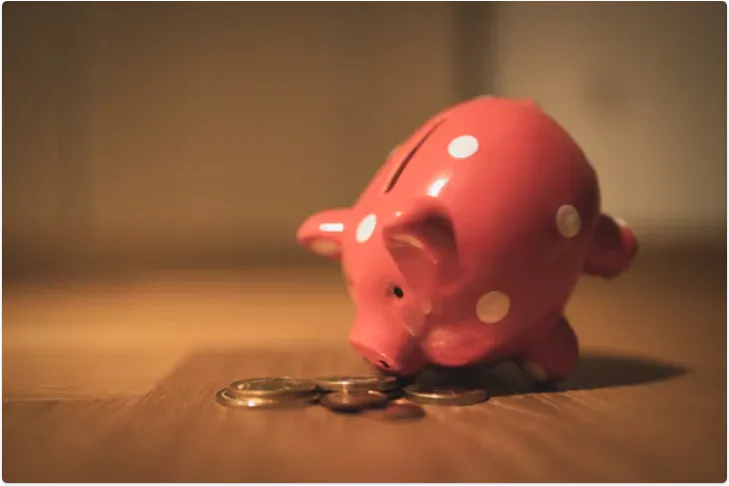 pink piggy bank on front legs sniffing money